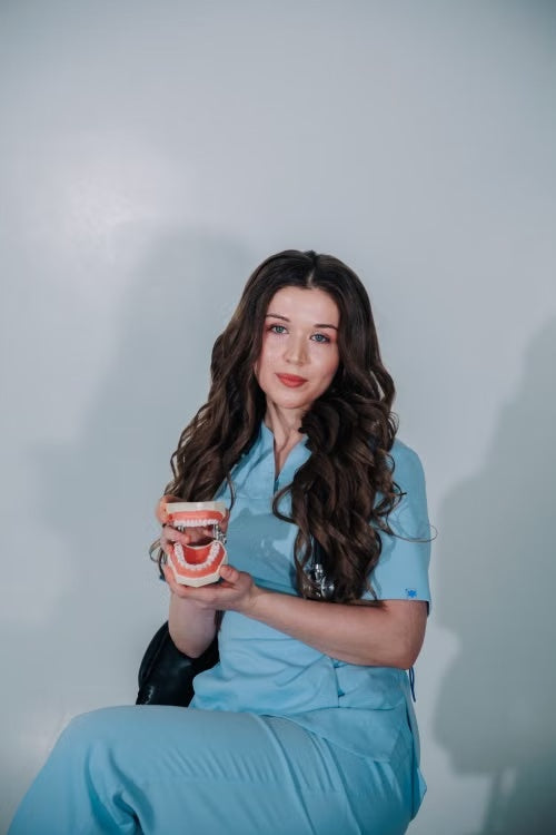 Katie, founder of Soleva, in blue scrubs holding a dental model